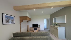 A living room with a sofa, television, wooden beam ceiling, and a framed picture on the wall. - Bird Paradise (POMMIERS)
