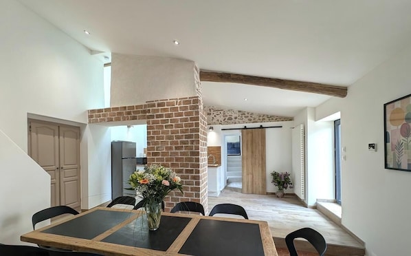 A dining area with a brick accent wall, a wooden table, and chairs.