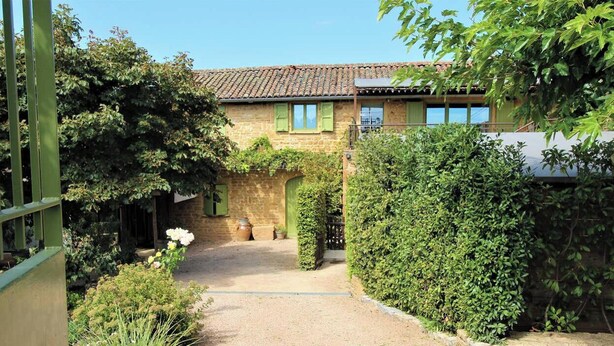 A stone building with a tiled roof, a gravel path, and lush greenery. - Gîte de Pelozane - CHARNAY (CHARNAY)