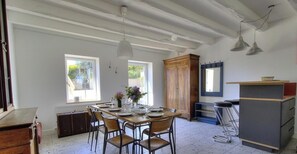 Un coin repas avec une table en bois dressée pour quatre personnes, un buffet et un miroir au mur.