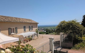 A building with a tiled roof, a covered outdoor area, and a view of the countryside.