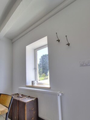 Une piĂšce avec une fenĂȘtre, un radiateur et une valise.