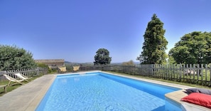 Une piscine rectangulaire dotĂ©e dâune terrasse en bois et de chaises longues, entourĂ©e dâune clĂŽture en bois et dâarbres.