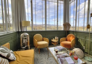 A conservatory with wicker chairs, a brass instrument, and a view of the countryside. - La Maison Laetitia - DENICE (DENICE)