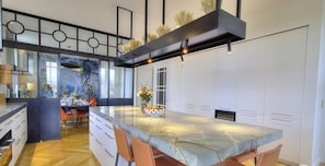 A modern kitchen with a large island, white cabinetry, and a decorative aquarium. - La Maison Laetitia - DENICE (DENICE)
