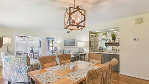 A dining area with a wooden table, woven chairs, and a hanging light fixture.