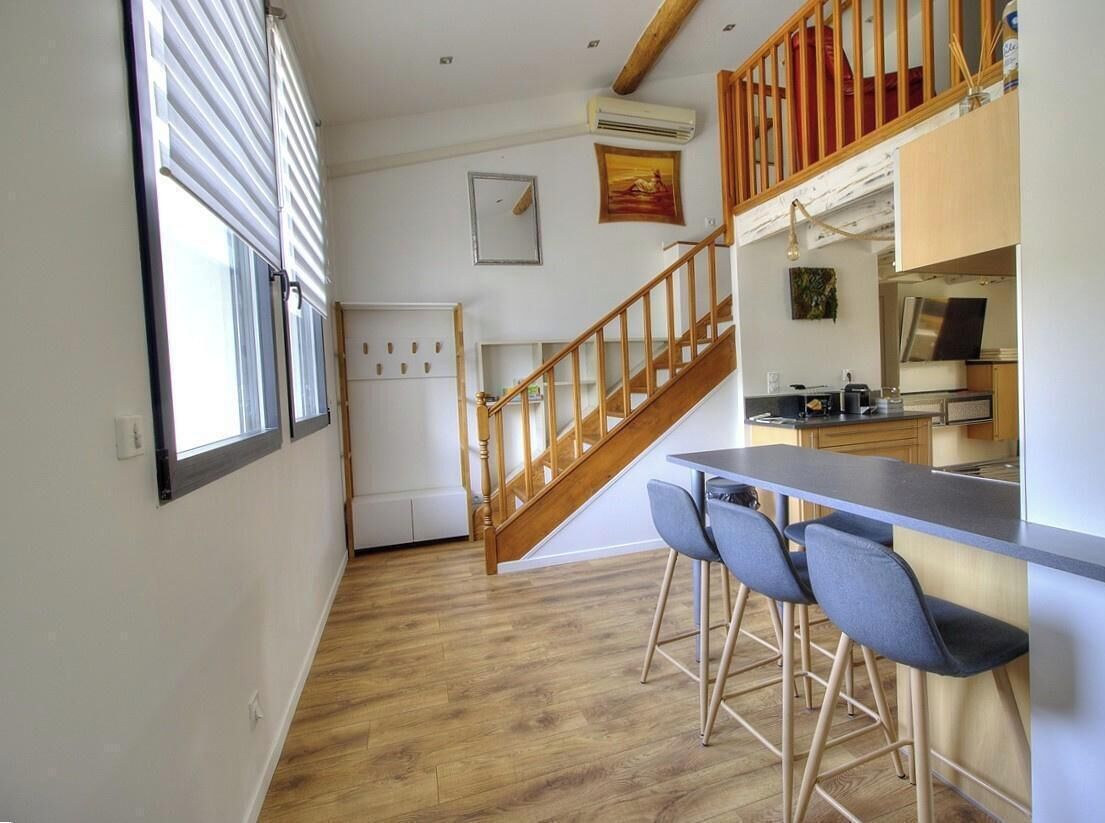 Een keuken met een houten trap, een bar voorzien van krukken, en een koelkast.