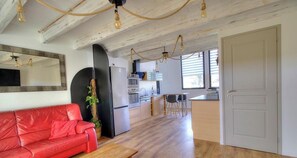 Eine moderne Küche mit Holzsäcken, einem Kühlschrank und einer Essecke mit einem roten Sofa und einem Holztisch.