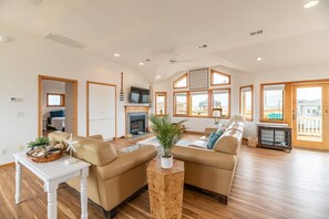 A spacious living area with a fireplace, large windows, and a view of the beach. - Ocean Aire - 4x4 Carova Beach, Ocean View, Hot Tub, Large Decks, Pets OK, Kayaks (Carova Beach)