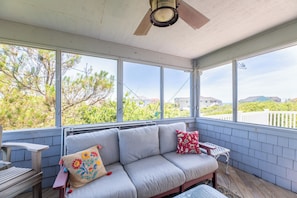 Eine überdachte Veranda mit einer Couch, einem Tisch und einem Deckenventilator.