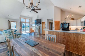 Ein geräumiges Wohnzimmer mit einem Holzesstzimmer, eine Küche mit weißen Schränken und ein großes Fenster mit Blick.