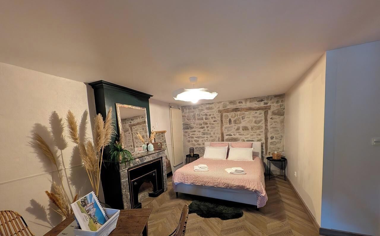 Ein Schlafzimmer mit Steinwand, einem Bett mit gestreifter Bettdecke, einem Kamin und einem Spiegel.