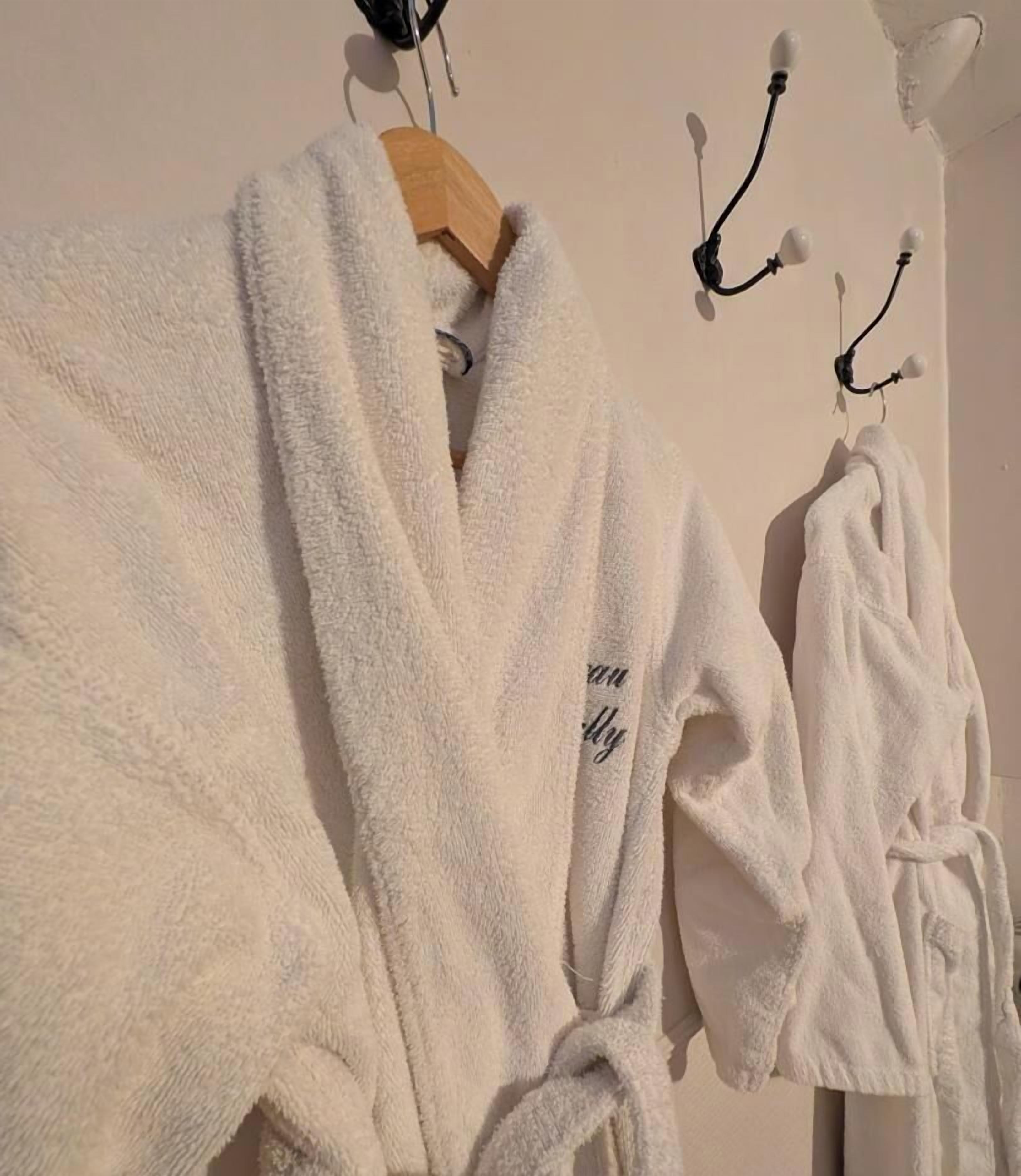 A white robe with a text on it, hanging on a wooden hanger.