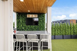 Ein Außenbereich mit Bar, Holzboden, Flachbildfernseher und einer Bar.