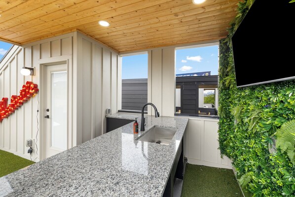 Eine Küche mit Granit Arbeitsplatte, einem schwarzen Wasserhahn und einem Fenster mit Blick auf ein Gebäude.