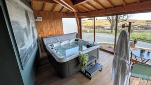 En træterrasse med et boblebad, et håndklædetørrestativ og et maleri.