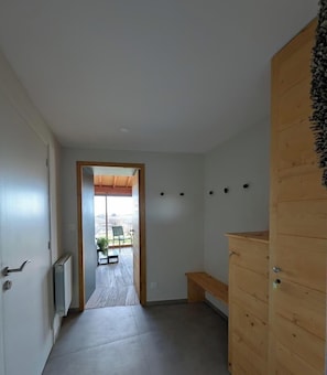 A hallway leading to a balcony with a bench, wooden cabinets, and a radiator. - Charme des Bruyères - LANTIGNIE (LANTIGNIE)