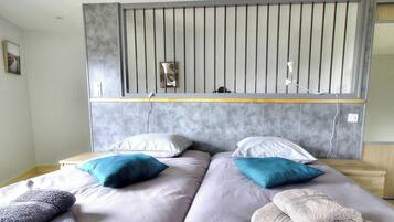 A bedroom with two beds, a headboard with vertical slats, bedside tables, and a mirror.