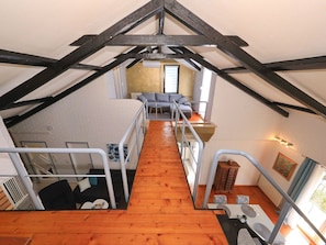 Ein Loftzimmer mit Holzboden, einer Couch, einem Esstisch und einer Küchenzeile.