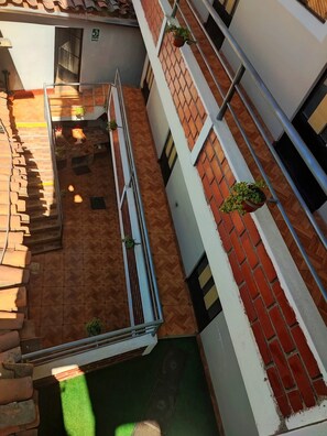 A courtyard with a brick floor, potted plants, and a metal railing. - THE SHELTER OF MY DREAMS (Yungay)
