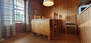 A wooden interior with a dining table, chairs, a hanging light fixture, and a window. - Sauna | Wi-Fi | Terrace | Wood stove | Cable TV (Lofsdalen)