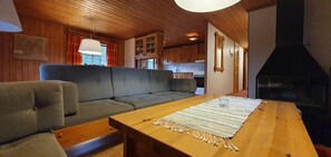 Ein gemütliches Blockhäuschen-Interieur mit einer Couch, einem Holztisch und einem Kamin.
