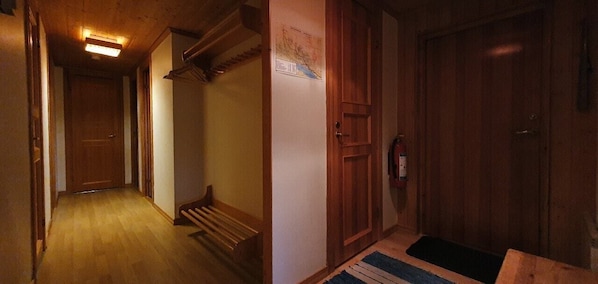 Ein Korridor mit Holzboden, einer Bank, einer Tür mit Feuerlöscher und einer Karte an der Wand.