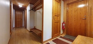 Ein Korridor mit Holztüren, einem Feuerlöscher und einer hölzernen Bank.