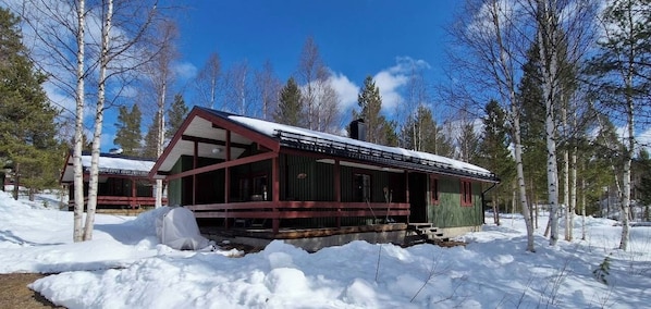 Eine Hütte mit einer großen Terrasse, umgeben von Schnee und Bäumen.