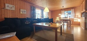 Ein gemütliches Zimmer mit einer Couch, einem Esstisch und einer Küchenzeile.