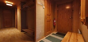 Ein Korridor mit Holztüren, einem Feuerlöscher und einem kleinen Tisch.