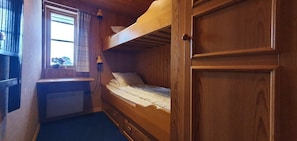 Ein Schlafzimmer mit Etagenbett aus Holz, einem Fenster, einer Heizung und einer Tür.