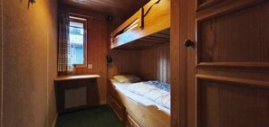 A bunk bed room with a desk and a window with curtains.