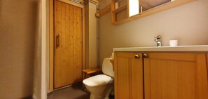 A bathroom with wooden cabinets, a toilet, and a shelf with toiletries.