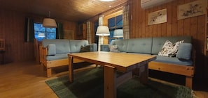 Ein Holzinnenraum mit einer Sofagarnitur, einem Tisch und einer Lampe.