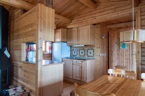 L’intérieur d’un chalet en bois comprend une cuisine, un coin repas et une cheminée.