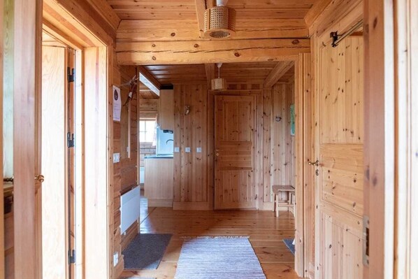 A wooden hallway with a bench, a door, and a hanging light fixture.