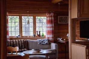Ein gemütliches Blockhaus-Interieur mit einer Couch, einem runden Tisch und einem Fernseher.