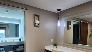 Een badkamer met een wastafel, spiegel, stoel en een potplant.