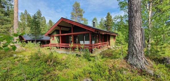 Eine Hütte mit rotem Anstrich, umgeben von Wald.