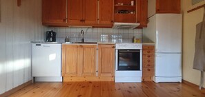 Eine Küche mit Holzausstattung, einem weißen Kühlschrank, einem Herd und einem Geschirrspüler.