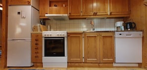 Eine Küche mit Holzausstattung, einem weißen Kühlschrank, einem Herd und einem Geschirrspüler.