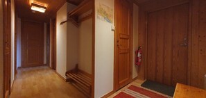 Un pasillo de madera con una puerta de madera, un extintor y un mapa en la pared.