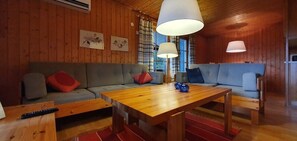 Un interior de madera con un sofá, una mesa de madera y dos lámparas.