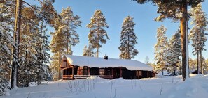 Eine Blockhütte, umgeben von schneebedeckten Bäumen.