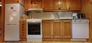 Eine Küche mit Holzausstattung, einem weißen Kühlschrank, einem Herd und einem Geschirrspüler.