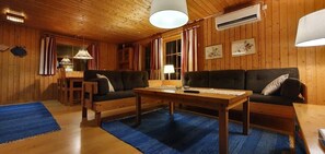 Ein Holzblockhaus-Innenraum mit einer Couch, einem Tisch und einem Essbereich.