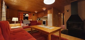 Ein gemütliches Blockhaushaus-Interieur mit Wohnbereich, Holzmöbeln, Kamin und Küche.