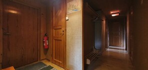 Ein Korridor mit Holztüren, einem Feuerlöscher und einer Karte an der Wand.