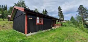 Eine schwarze Holzhütte mit rotem Dach, einer Veranda und einem Schild mit der Nummer 87.